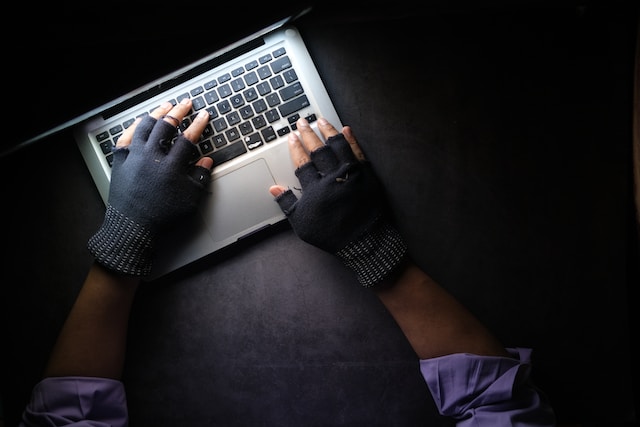 A person wearing gloves and using a laptop in the dark to symbolize a data breach